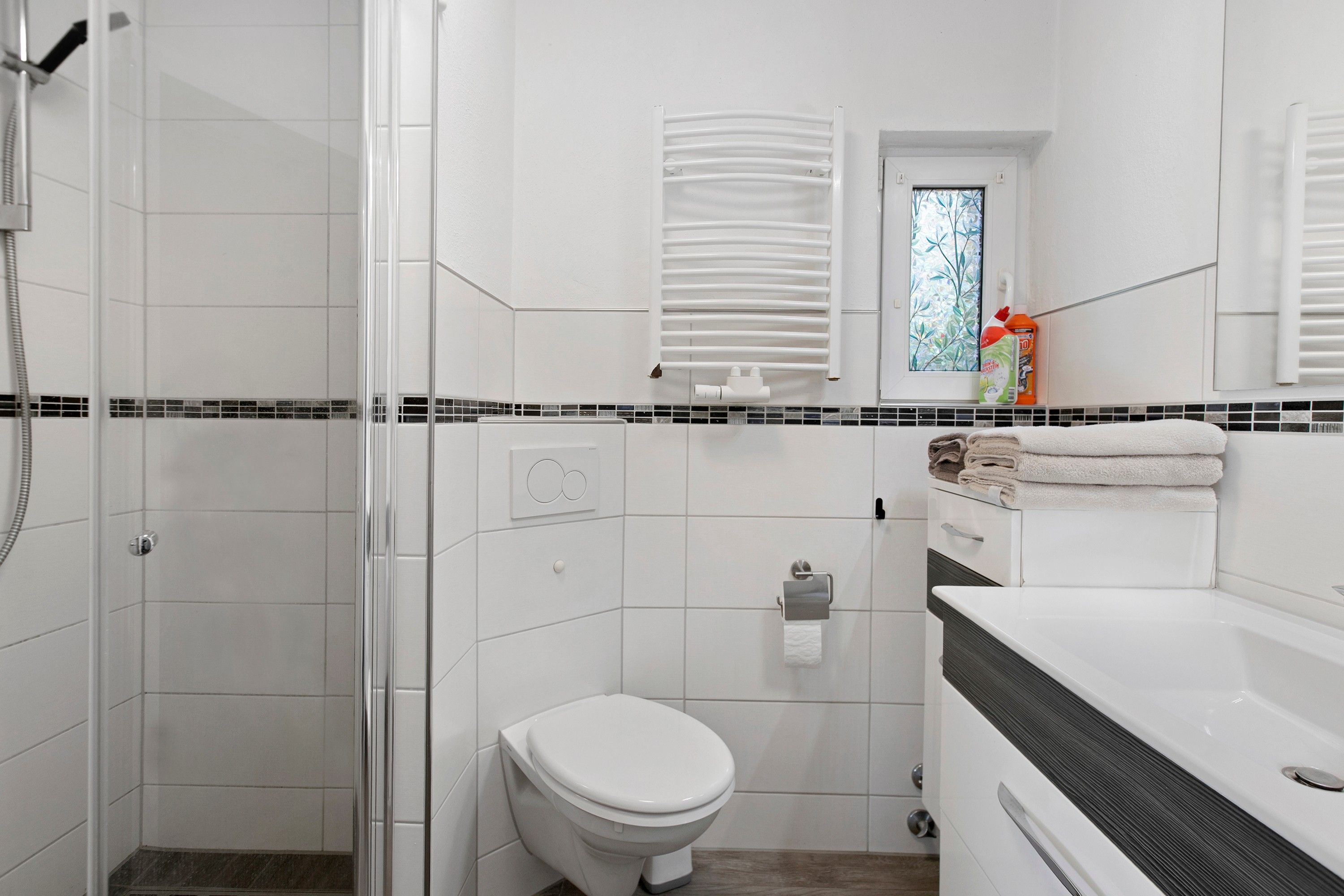 Een moderne badkamer met een douche, toilet en wastafel.