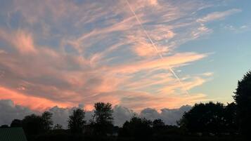 Un ciel au coucher du soleil, avec des nuages et une traînée de condensation.