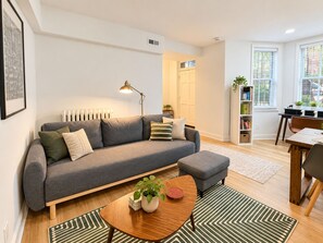 A modern living room with a sofa, coffee table, and a bookshelf. - 1BR in Logan Circle - DC Metro - We Host (Washington)