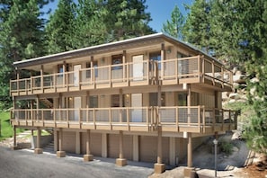 Un immeuble à plusieurs étages, doté d’un balcon au niveau supérieur, et entouré d’arbres.