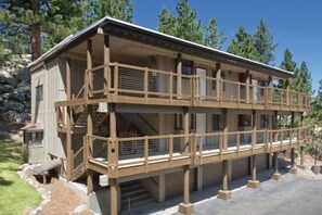 Une cabane en bois à deux étages, dotée d’un balcon, d’un escalier et de fondations en pierre.