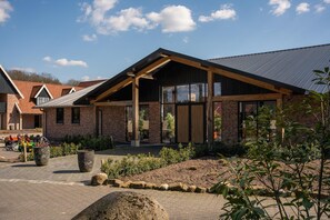 A modern building with a brick facade, large windows, and a sloped roof. - Landgoed 't Borghuis - De Boomgaard | 4–16 people (Losser)