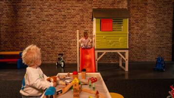A child playing with toys on a table in a room with a brick wall.