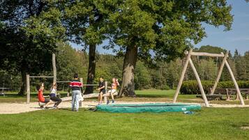 A playground with a swing set, a trampoline, and a sandpit.