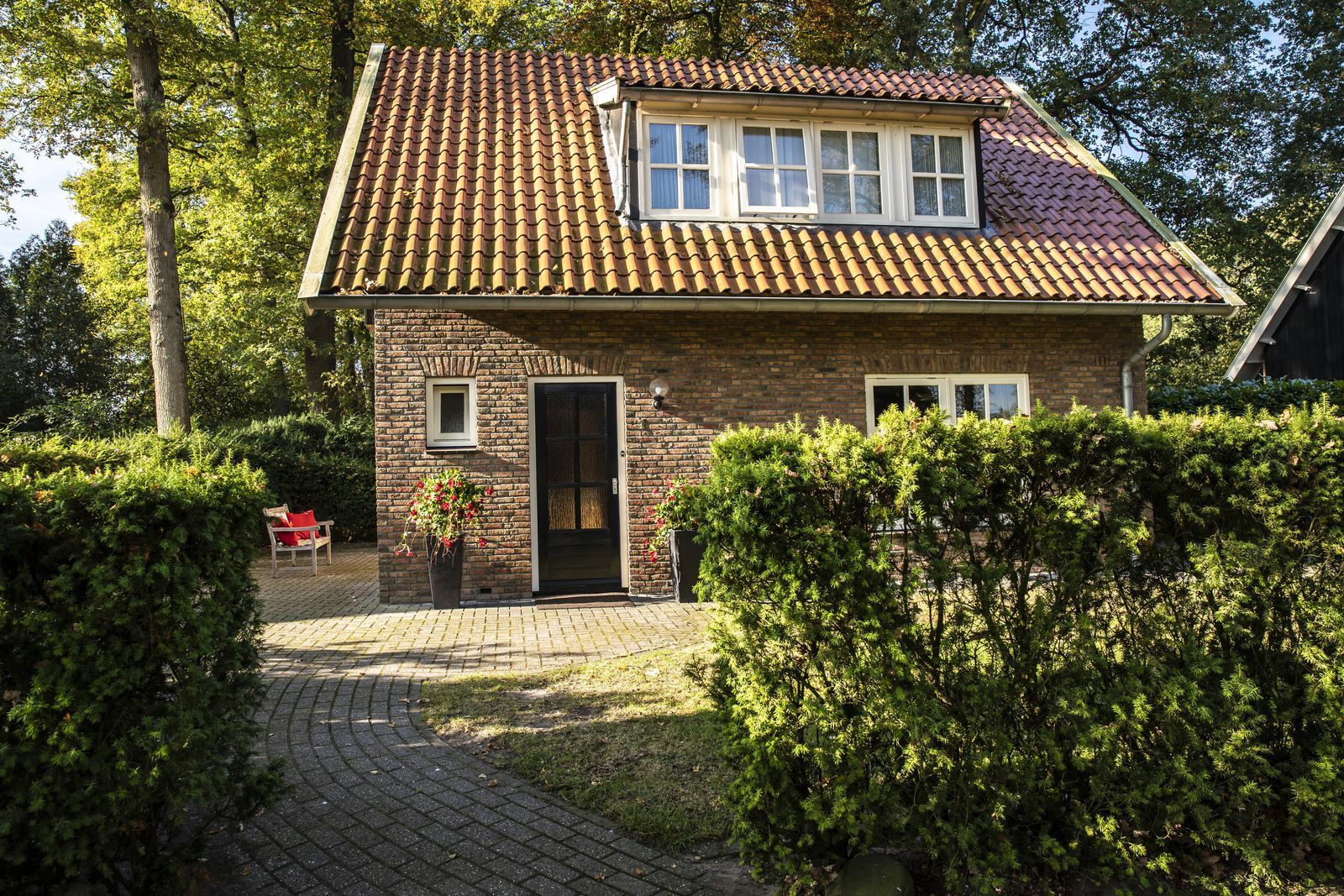 Une maison à deux étages, avec un toit en tuiles, une façade en briques et une allée pavée.