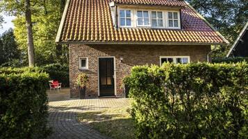 A two-story house with a tiled roof, a brick facade, and a paved driveway.