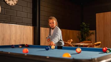 Een pooltafel met ballen, een dartbord en een houten wand.