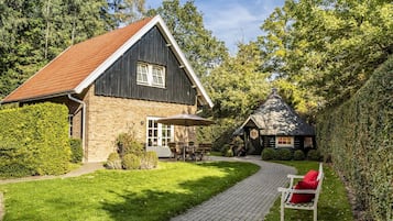 A house with a brick exterior, a red-tiled roof, and a small attached structure with a conical roof.