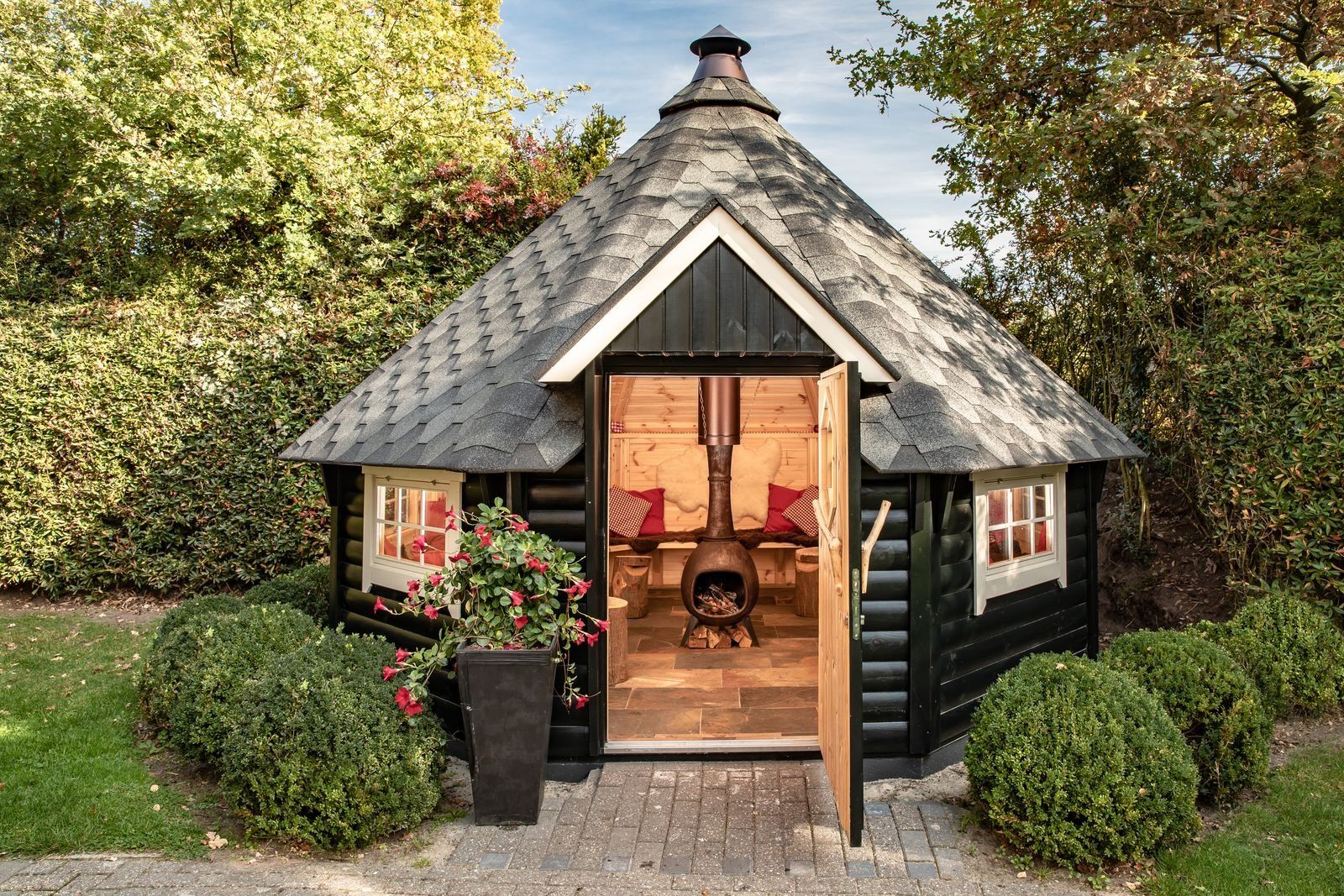 Une cabane en rondins avec une cheminée, une porte en bois et une fenêtre.