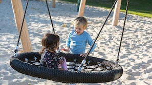 Two children playing on a tire swing in a sandy area. - Landgoed 't Borghuis - De Sterre | 10–45 people (Losser)