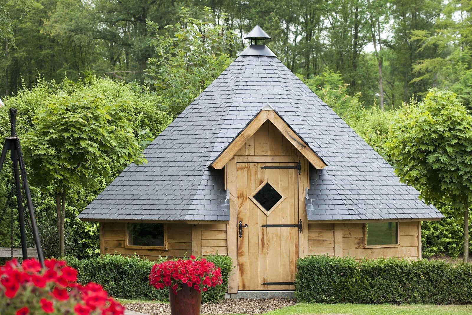 A small wooden structure with a steeply pitched roof, a door with a diamond-shaped window, and a small triangular roof ornament.