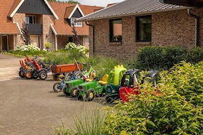 Ein Wohngebiet mit einer Reihe bunter Spieltraktoren vor einem Ziegelhaus.