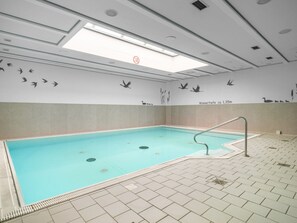 An indoor swimming pool with a tiled floor, a metal ladder, and wall murals of birds and plants. - 4.4/t3 Holiday Home Park \"freesenbruch\" (Zingst)