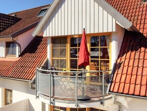 A residential building with a balcony featuring a metal railing and a red umbrella. - 4.4/t3 Holiday Home Park \"freesenbruch\" (Zingst)