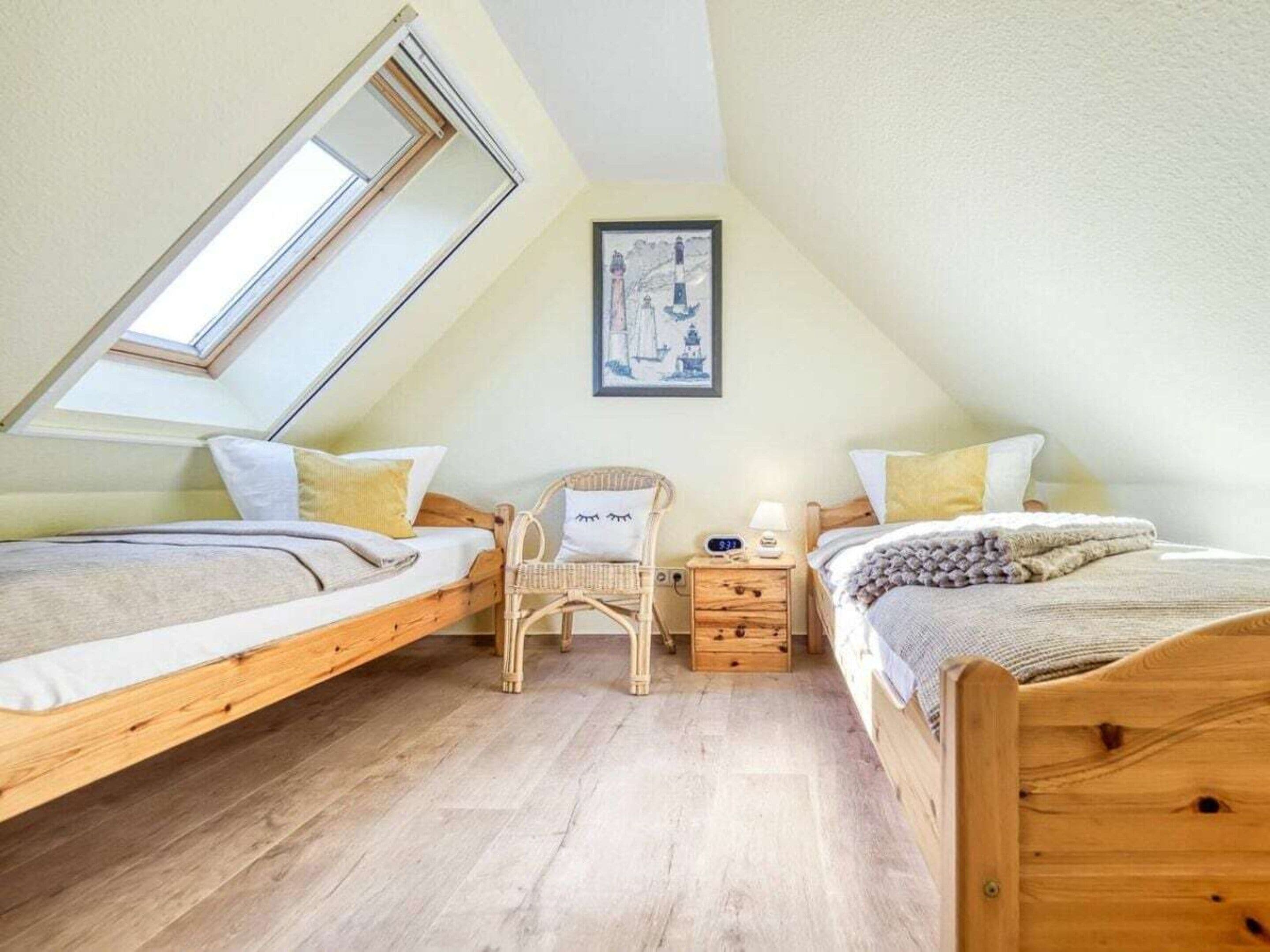 Ein Schlafzimmer mit zwei hölzernen Betten, einem Oberlicht, einem kleinen Stuhl und einem Nachttisch mit Lampe.