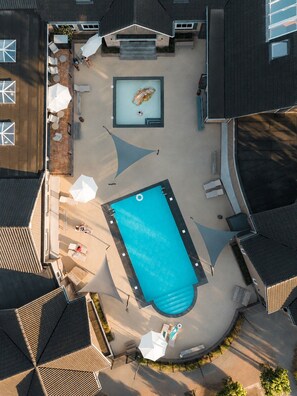 Eine Vogelperspektive zeigt ein Wohnanwesen mit Swimmingpool, Sitzgelegenheiten im Freien und einer überdachten Terrasse.