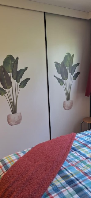 Ein Zimmer mit einem Bett, einem roten Handtuch und zwei an der Wand befestigten Blumentöpfen.