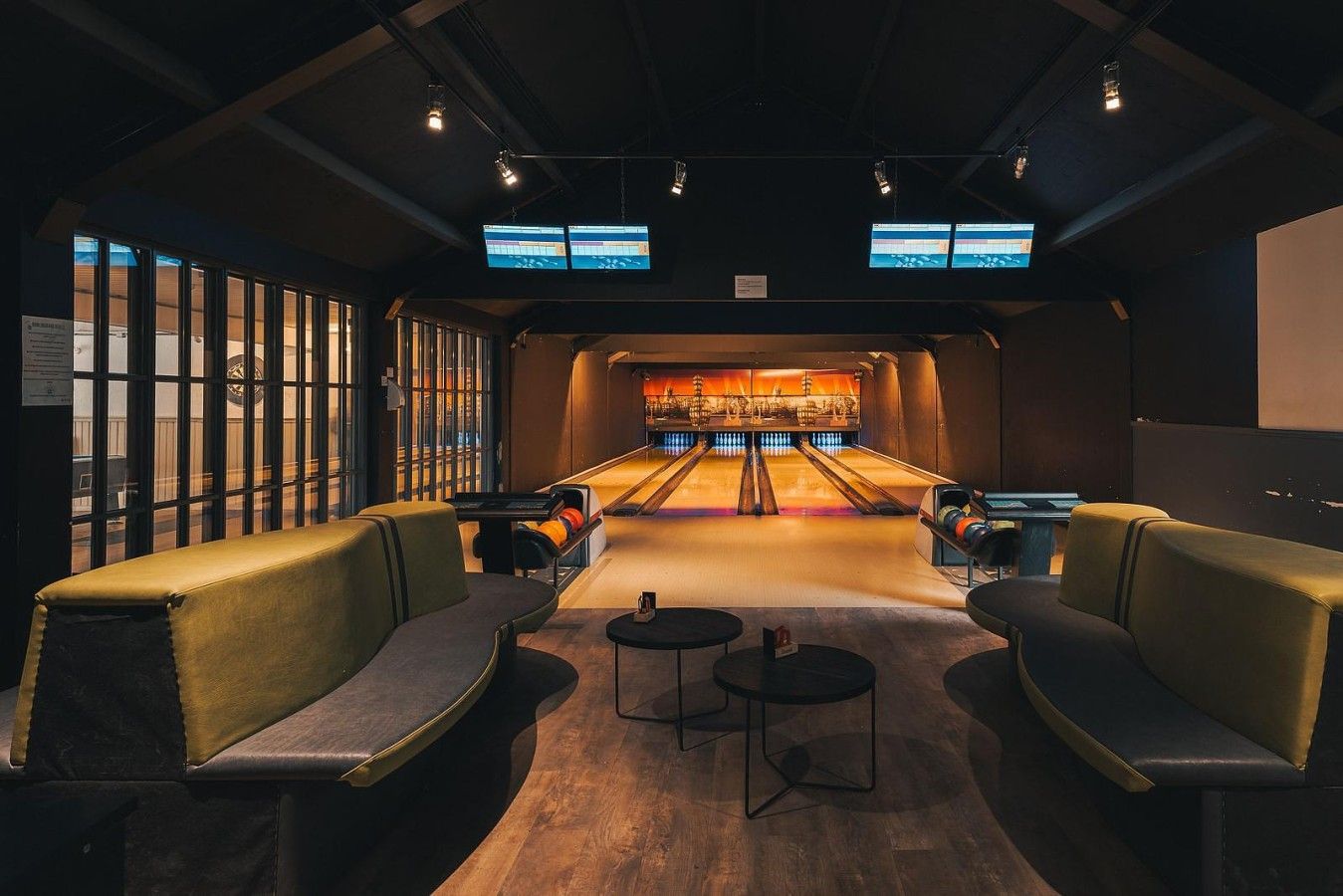 A bowling alley with seating and multiple screens.