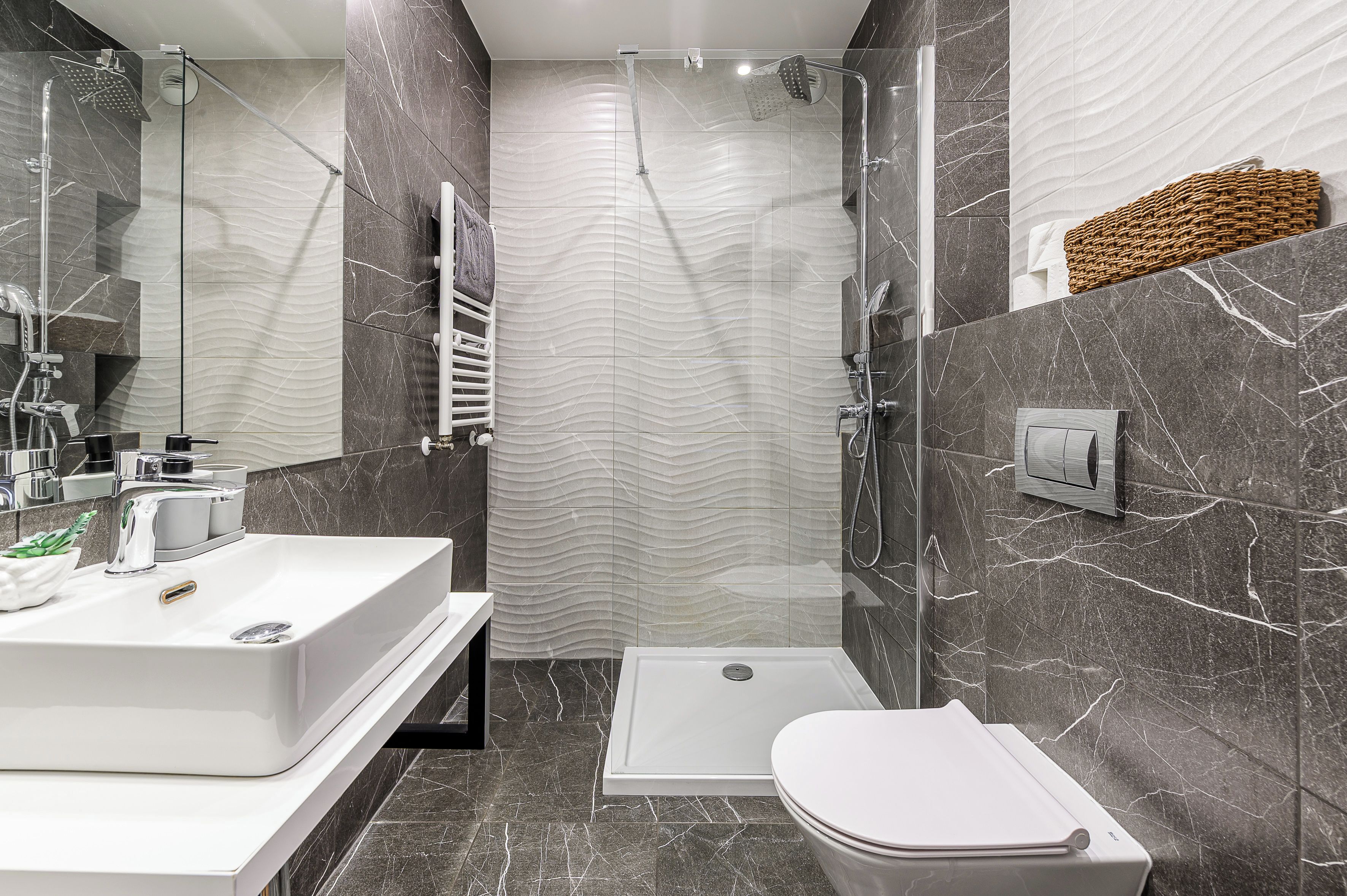 Een moderne badkamer met een wit wastafelmeubel, een toilet en een douche.