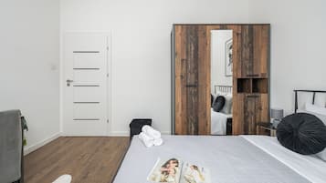 Un dormitorio moderno con cama, armario, silla y un pequeño cesto de basura.