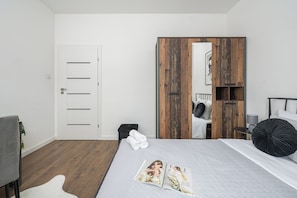 Un dormitorio moderno con cama, armario, silla y un pequeño cesto de basura.