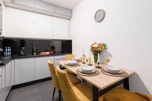 Una cocina moderna con armarios blancos, una mesa de comedor con platos, vasos y un jarrón de flores.