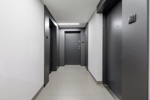 A corridor with doors on both sides, a tiled floor, and a ceiling with recessed lighting. - Lumina 3room Apt w/ Parking  (Łódź)