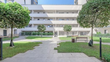 A courtyard with a central pathway, surrounded by greenery and benches.
