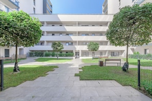 Un patio central con un sendero, rodeado de follaje y bancos.
