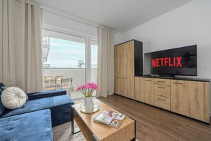 Una sala de estar moderna con un sofá, una mesa de centro y un televisor mostrando 'NETFLIX'.
