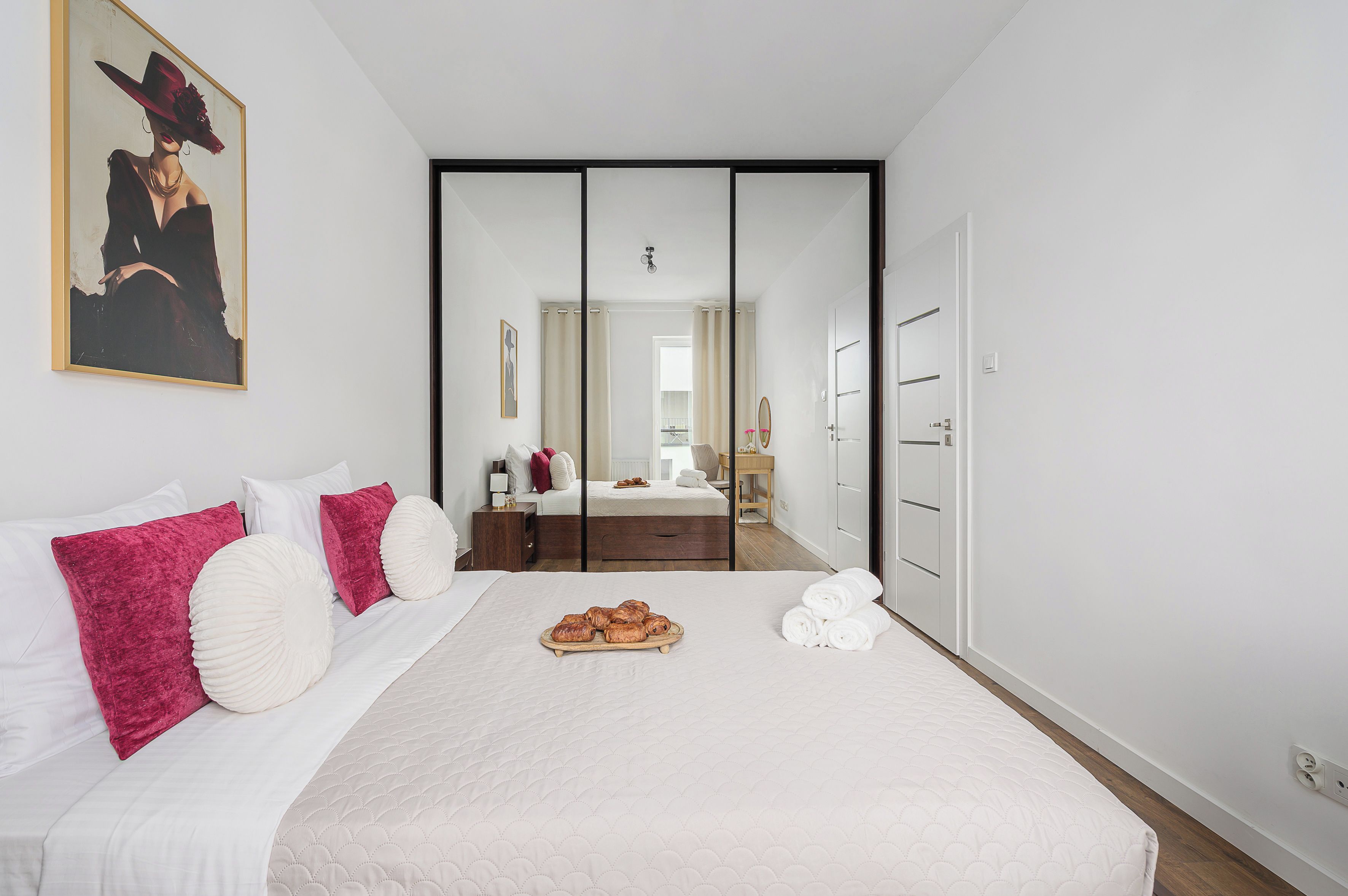 Habitación de hotel con cama, espejo, cómoda y un cuadro en la pared.
