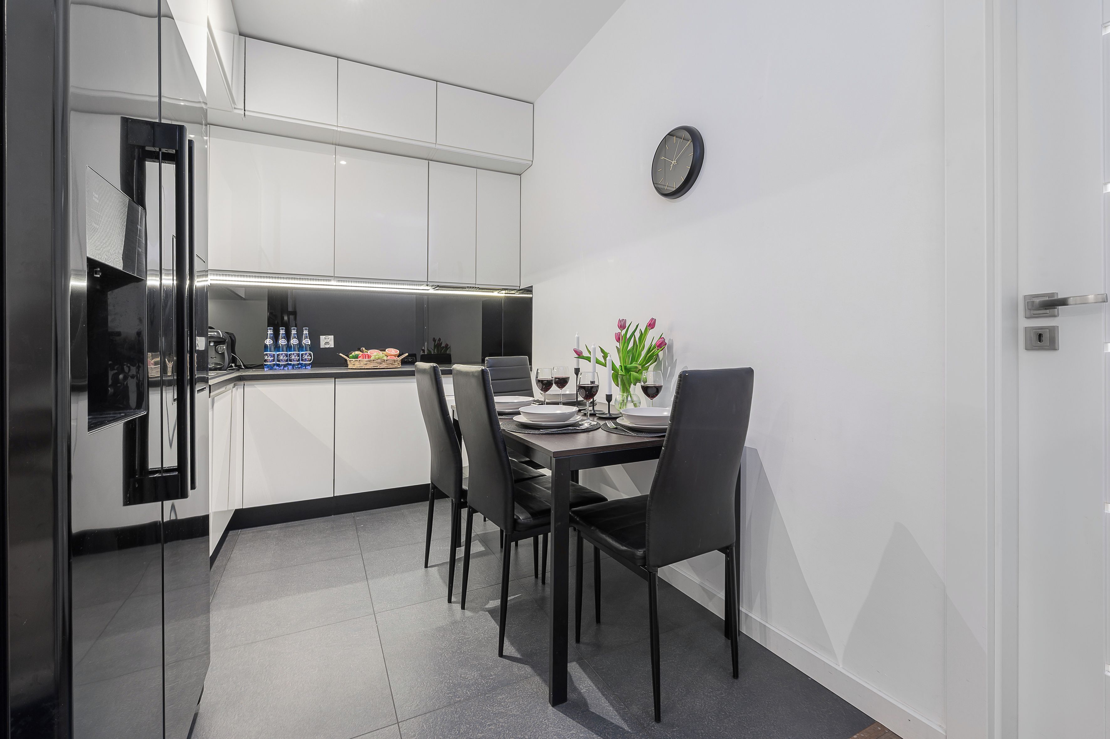 A modern kitchen with white cabinets, a built-in oven, and a dining area with a table set for two.