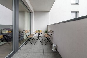 A small outdoor patio with a table and two chairs, a potted plant, and a lantern. - Lumina 3room Apt w/ Parking  (Łódź)