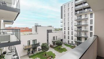 A modern apartment complex with balconies, a courtyard with seating, and a view of the cityscape.