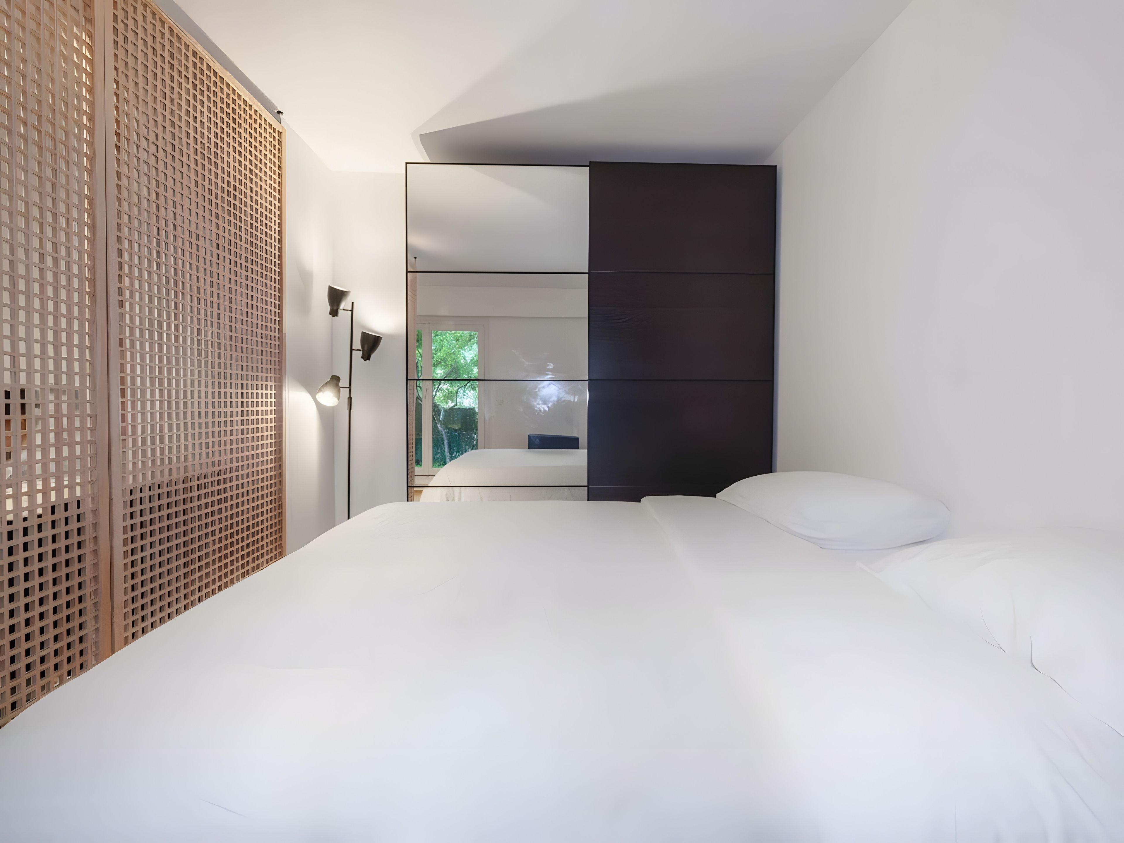 A modern bedroom with a large bed, a wardrobe, and a floor lamp.