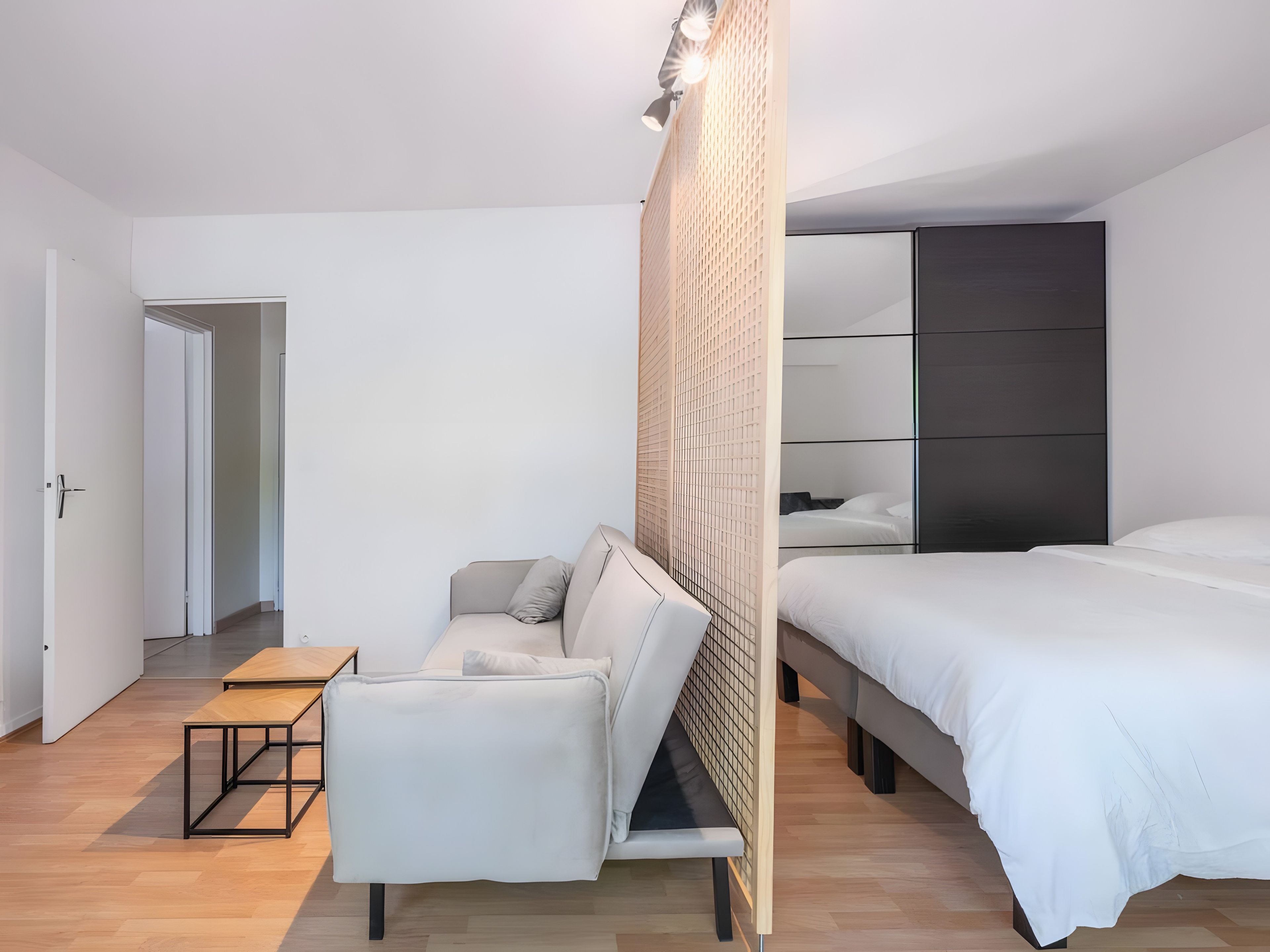 Een moderne slaapkamer met een bed, een bank, een klein tafeltje en een kledingkast.