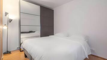 Een moderne slaapkamer met een bed, een kledingkast en een vloerlamp.
