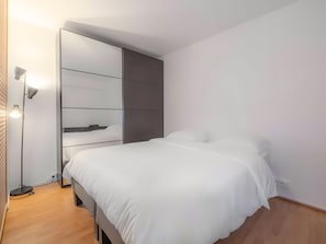 A modern bedroom with a bed, a wardrobe, and a floor lamp. - Apartment 'Le Cocon Chic-Jardin Privé-Parking' with Private Garden and Wi-Fi (Évry-Courcouronnes)