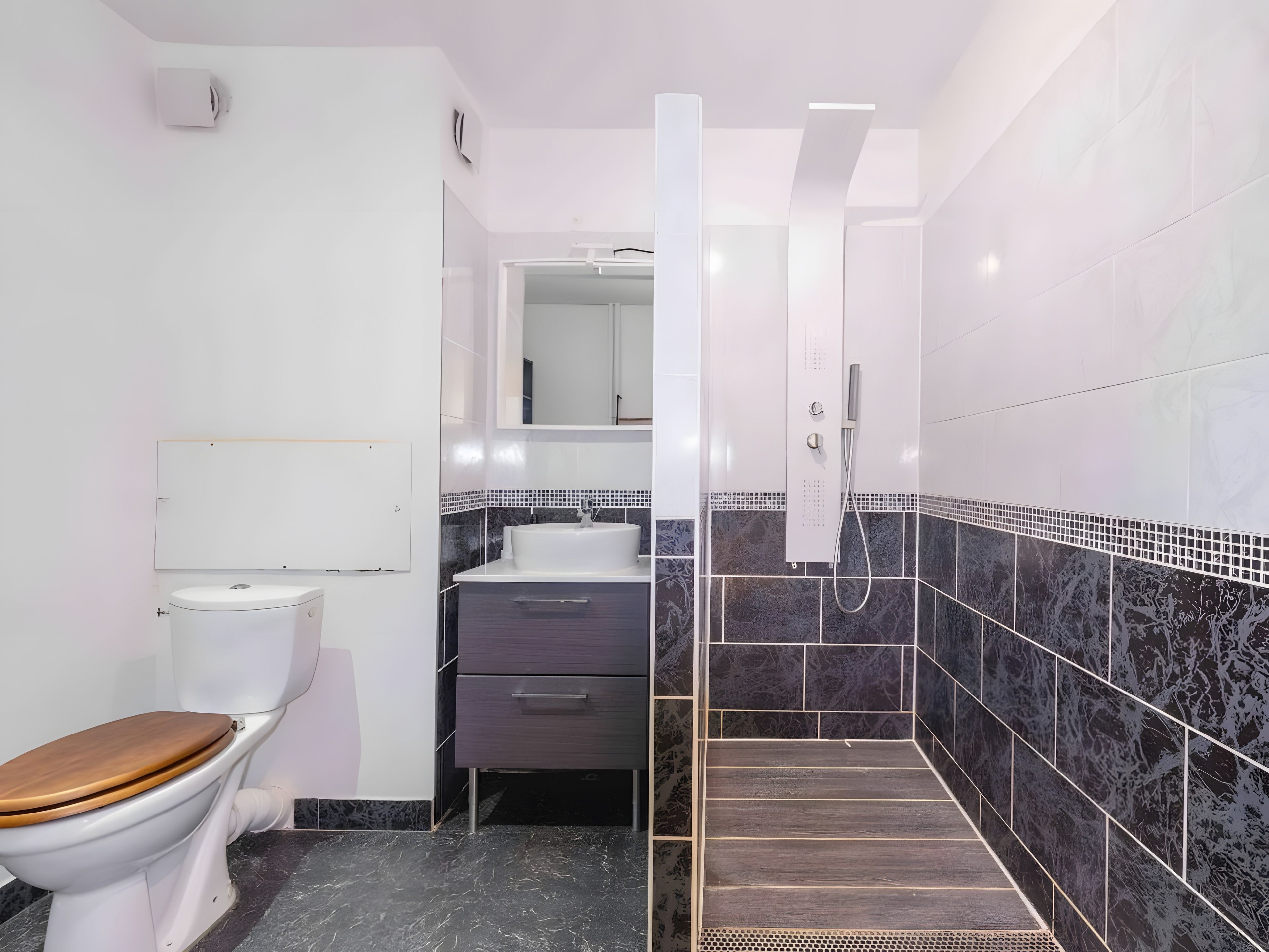 Une salle de bain moderne équipée de toilettes, d’un lavabo et d’un espace douche.
