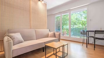 Een moderne woonkamer met een bank, een salontafel en een eethoek met stoelen.