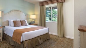 A hotel room with a bed, nightstand, lamp, window with curtains, and a carpeted floor. - WM BLOCK Reno 1br (Reno)