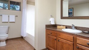 A bathroom with a toilet, sink, vanity, and mirror. - WM BLOCK Reno 1br (Reno)