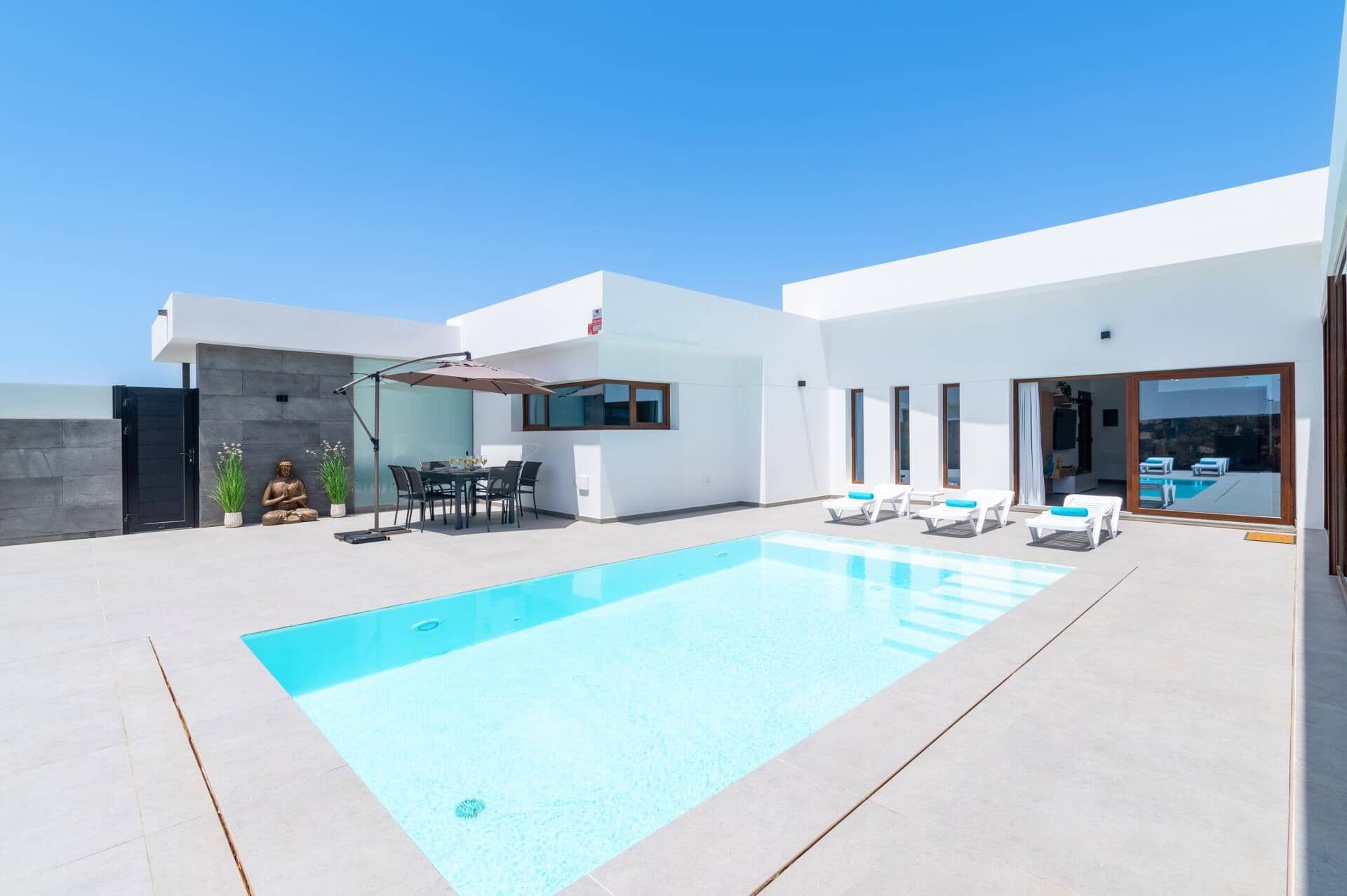 A modern outdoor pool area with a dining set and lounge chairs.