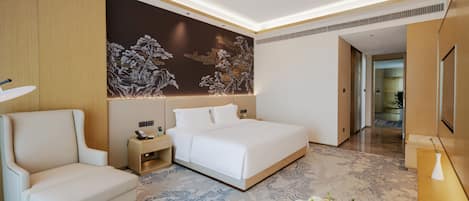 Una habitación de hotel moderna con una cama, una silla, una mesita de noche y un detalle decorativo en la pared.