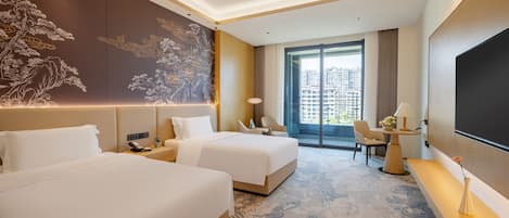 A hotel room with two beds, a large wall mural, a balcony with a view of buildings, and a flat-screen TV.
