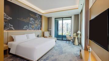 Een moderne hotelkamer met een groot bed, een flatscreen televisie, een bureau en uitzicht op de stad.