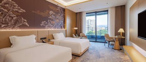 A hotel room with two beds, a desk, a chair, a TV, and a large window with a city view.