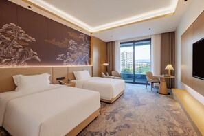 A hotel room with two beds, a desk, a chair, a TV, and a large window with a city view.