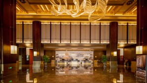 A spacious lobby with a reflective floor, a large decorative light fixture, and a reception desk with seating. - Grand Skylight Hotel Jingdezhen (Jingdezhen)
