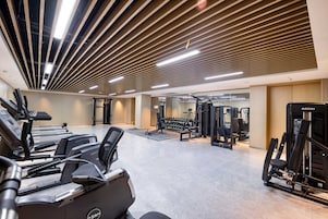 Un gimnasio con cintas de correr, máquinas de pesas y pesas libres.